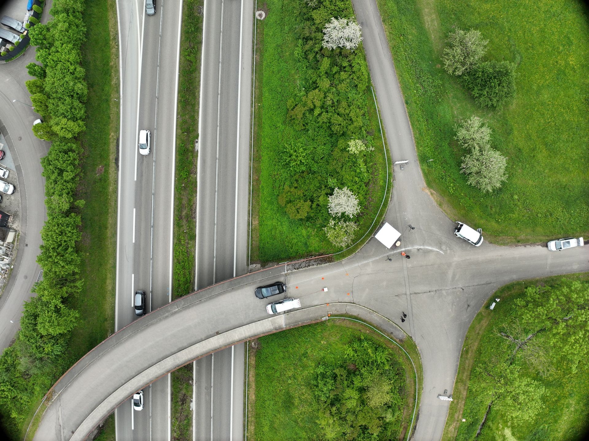 Aerial view of a highway intersection with multiple lanes, vehicles, and surrounding greenery.