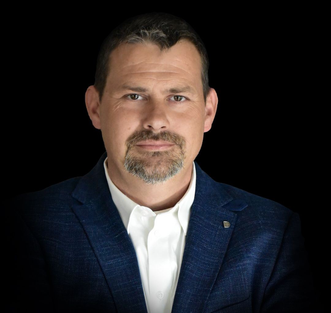 Person wearing a blue blazer over a white dress shirt, with a plain black background.